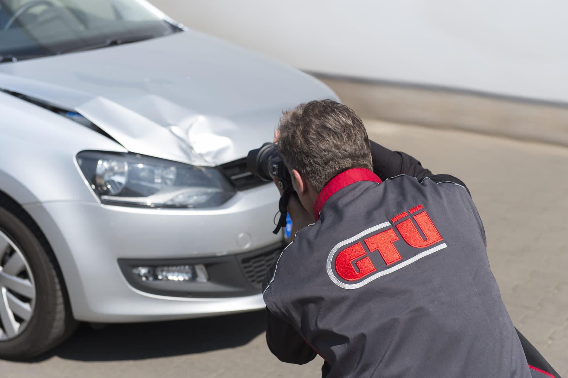 Sachverständiger fotografiert einen Frontschaden an einem Fahrzeug
